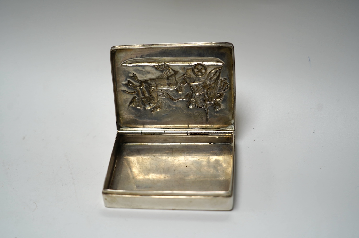 A German 800 standard white metal snuff box, the cover embossed with chariot scene, 78mm. Condition - fair to good